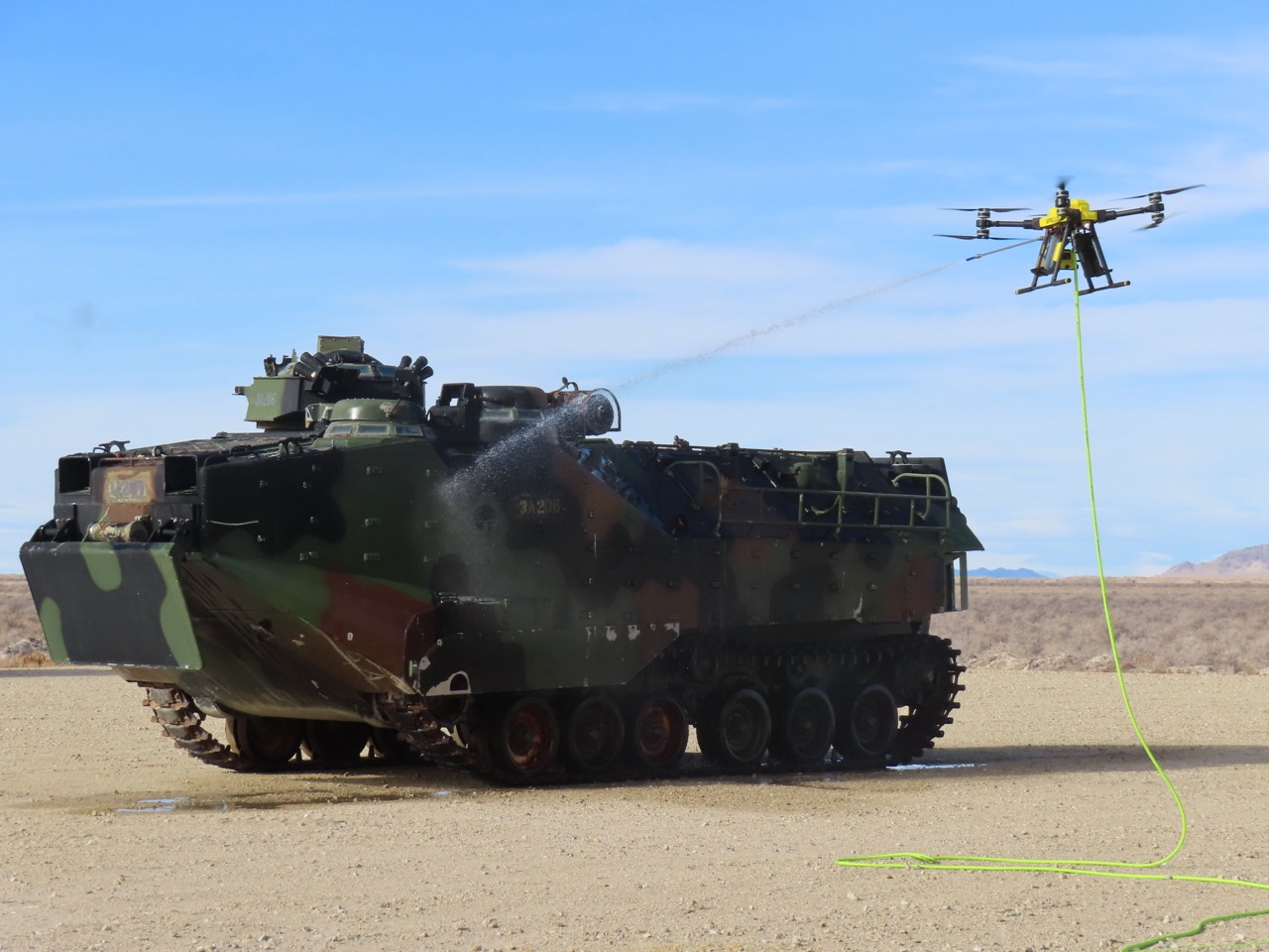 Apellix drone decontaminating military armored vehicle in desert